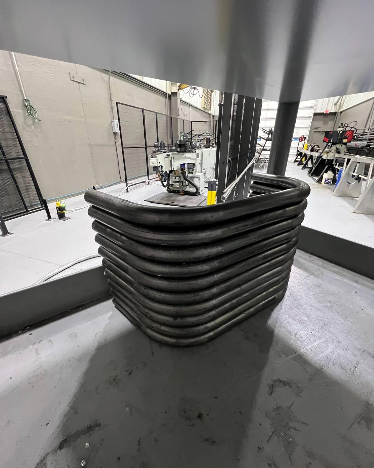 A stack of CNC bent tube hoops beside the bender