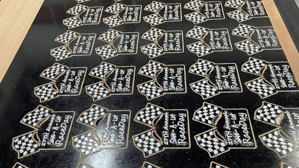 A production run of CNC cut checkered flag award plaques, nested on the sheet