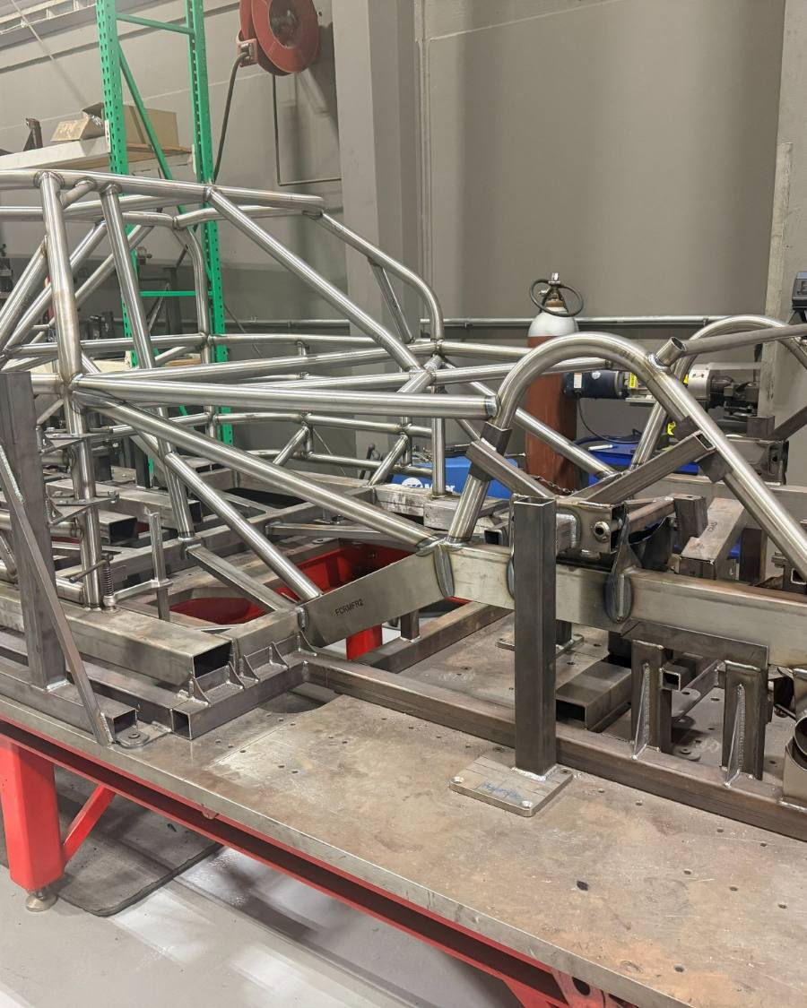 A motorsports chassis clamped in its fixture on the welding table