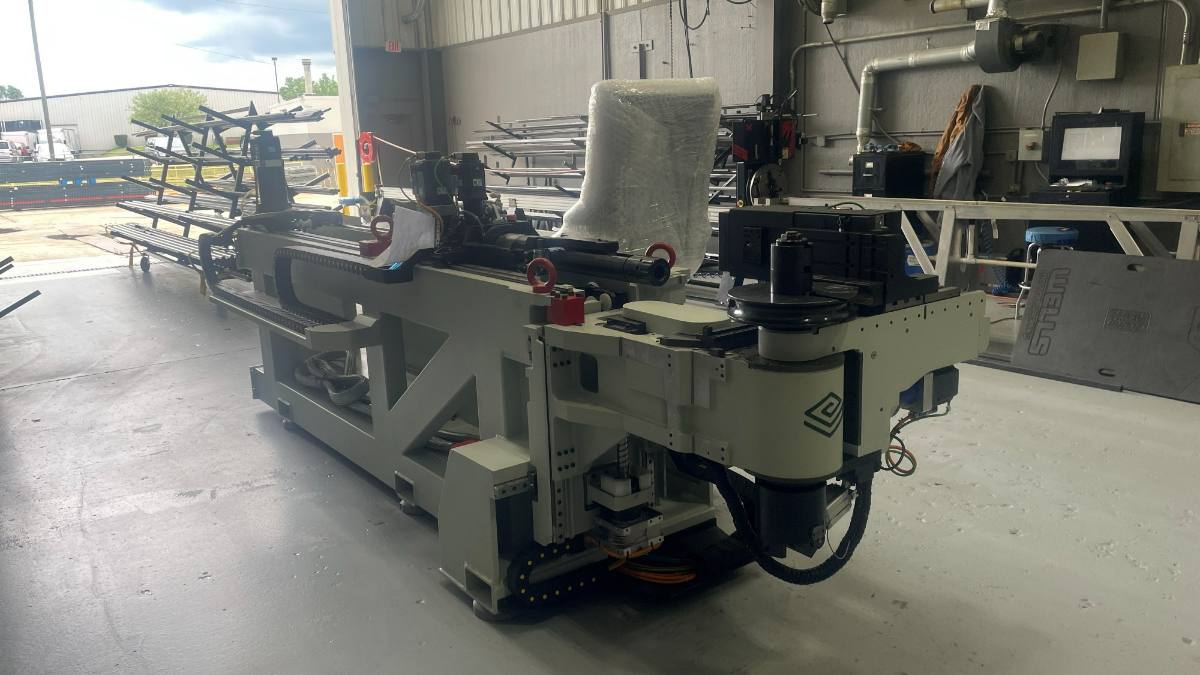 The CNC tube bender on the shop floor with the tube rack behind it