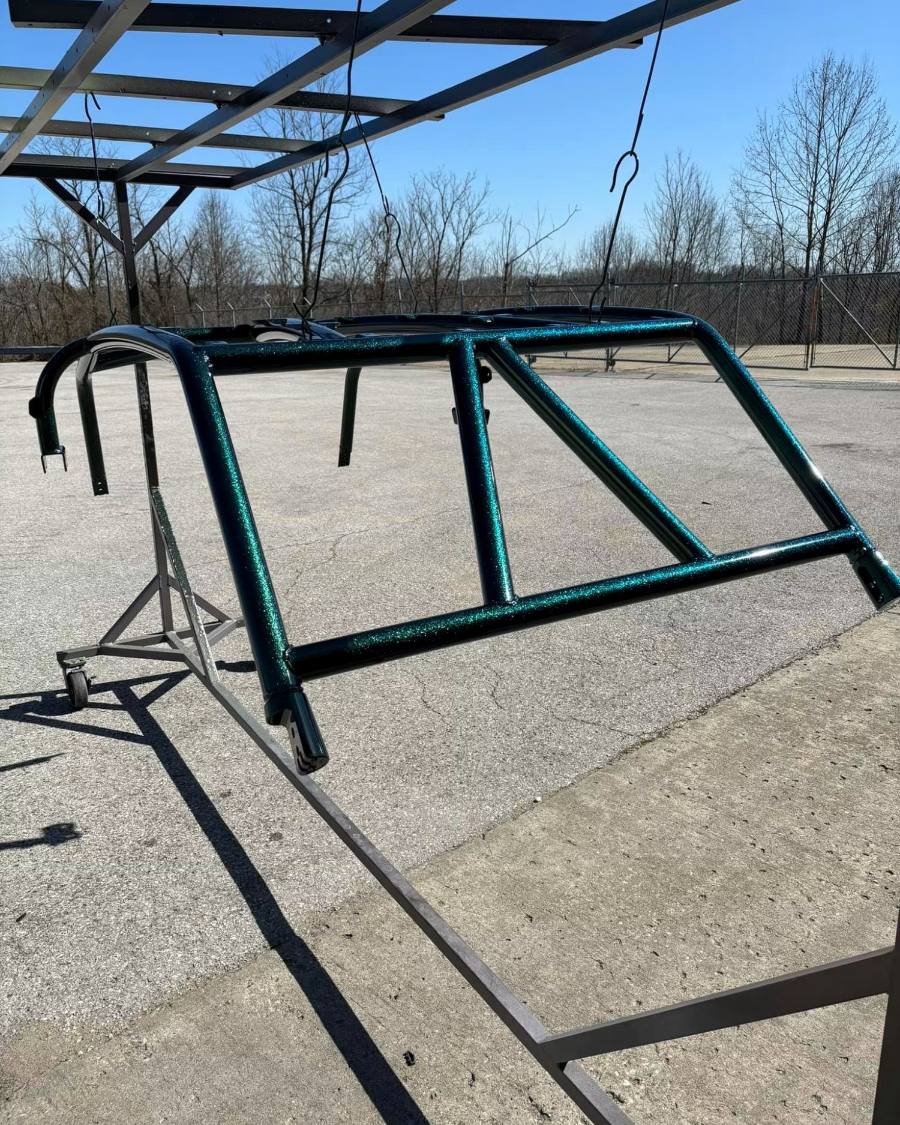 A cage finished in metallic teal powder coat, hanging on the outdoor rack