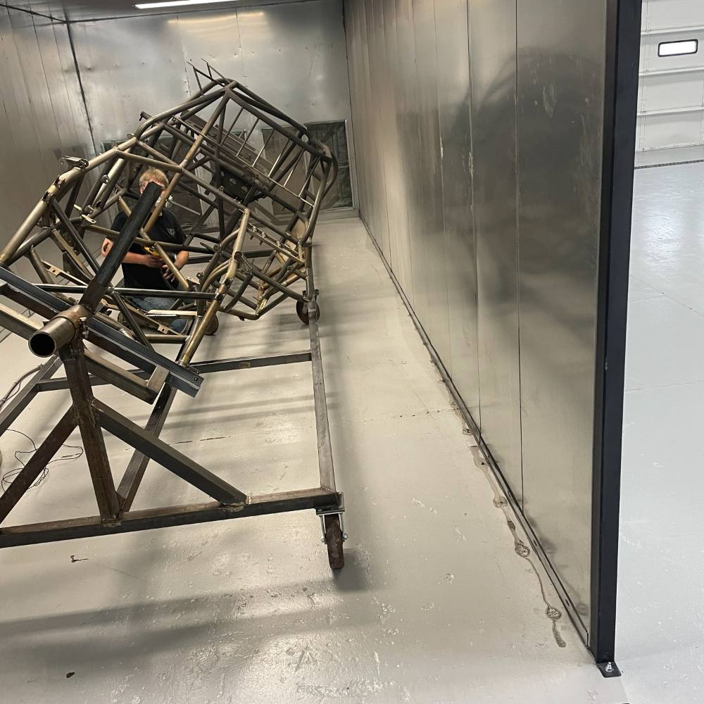 A chassis on its cart inside the booth being sprayed