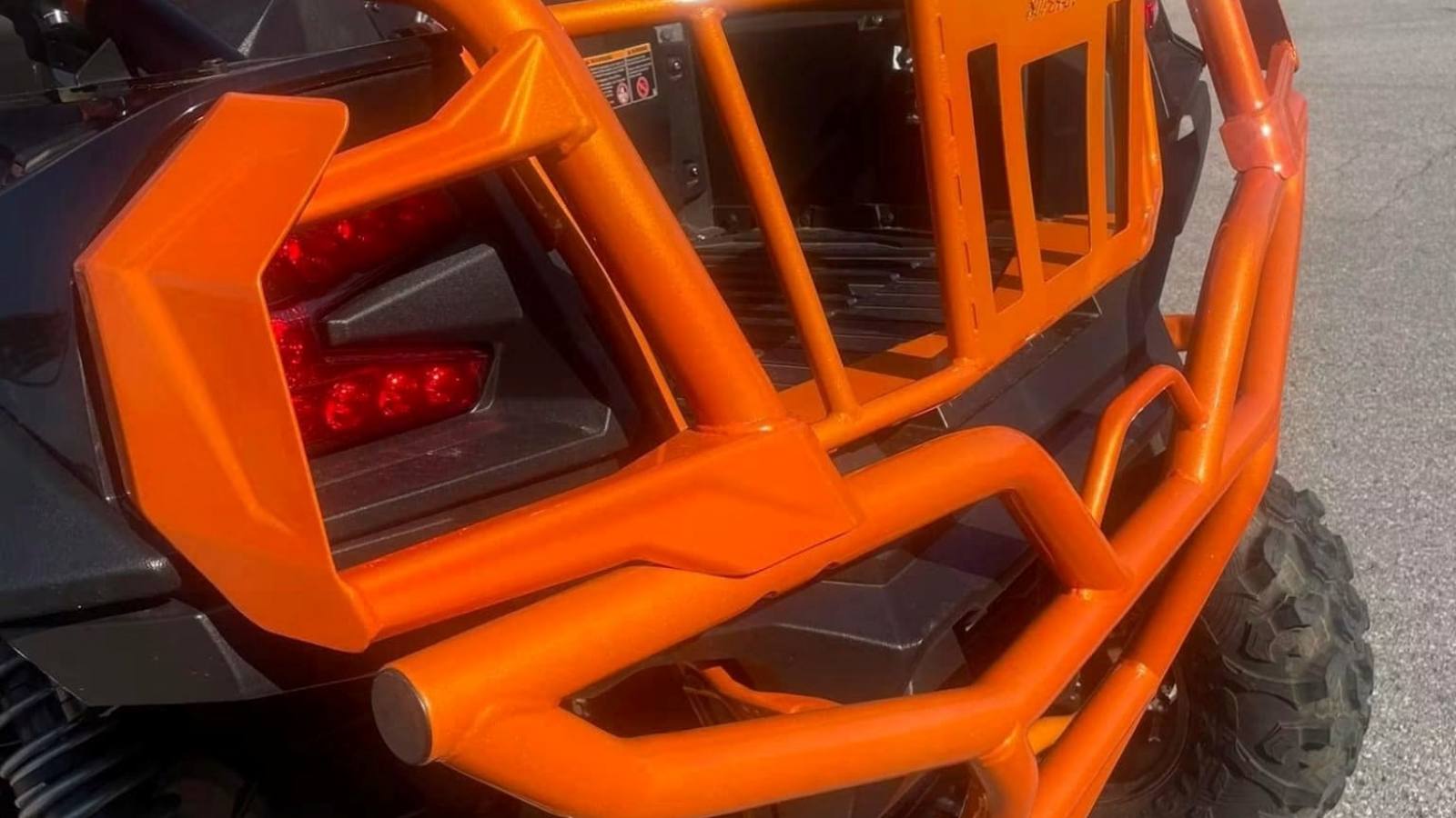 The rear of a side-by-side with a custom cage and rear bumper in orange powder coat