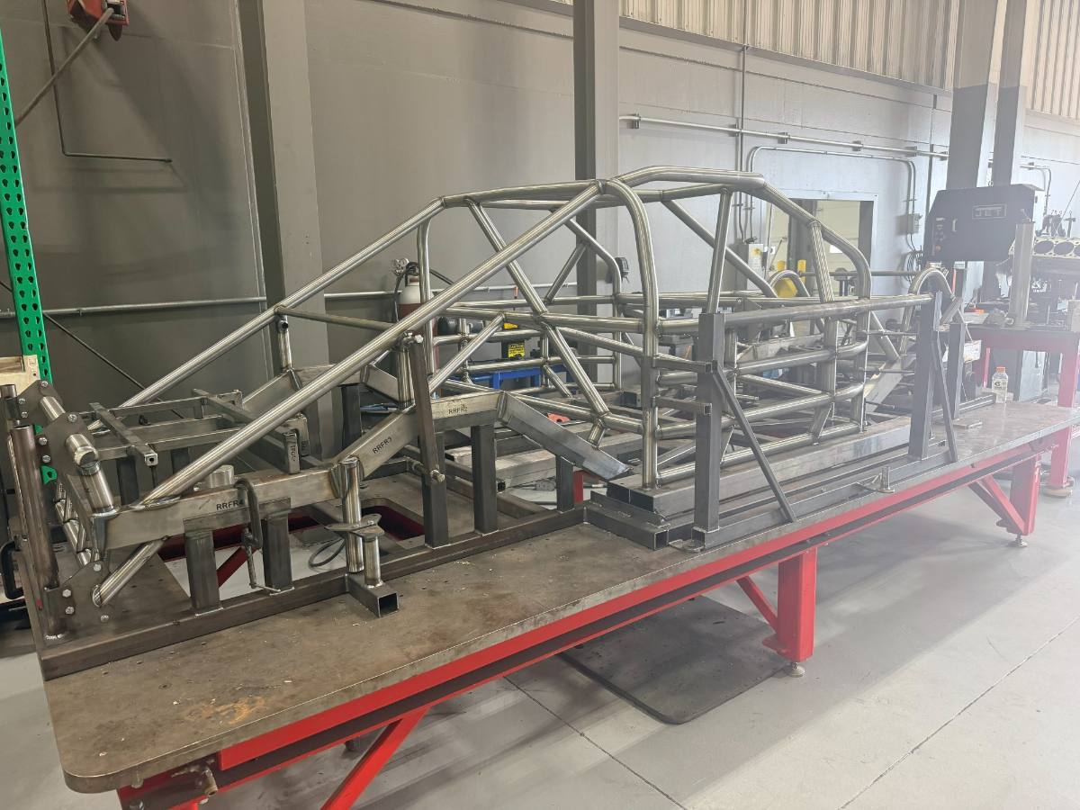 A motorsports chassis clamped on the fixture table part way through welding
